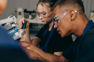 Two people wearing PPE working on a piece of mechanical equipment.