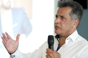 Entrepreneur Mo Chaudry holding a microphone and speaking to guests at the Summer Funding Summit