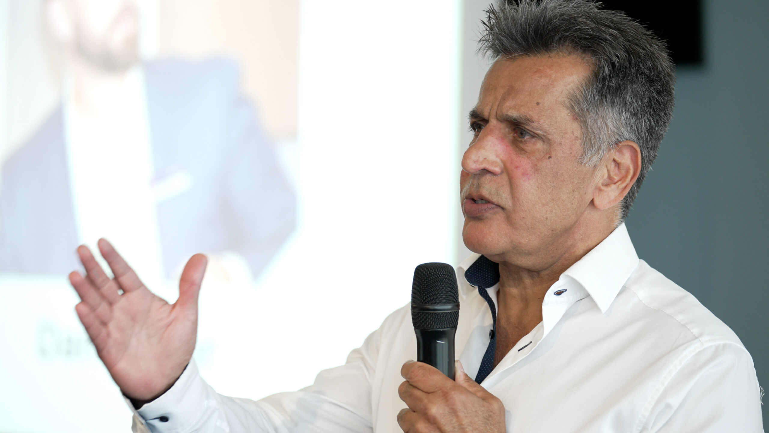 Entrepreneur Mo Chaudry holding a microphone and speaking to guests at the Summer Funding Summit