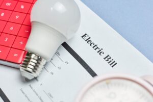 An electricity bill covered by a light bulb and a calculator.