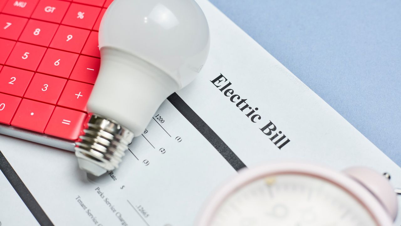 An electricity bill covered by a light bulb and a calculator.