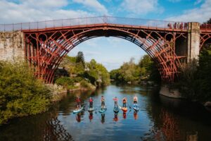The Iron Bridge in Telford. Under the bridge are six people kayaking on the water