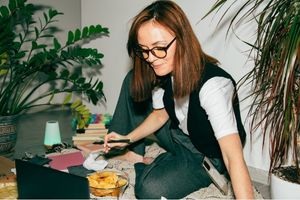 A [person sat on the floor working on a laptop.