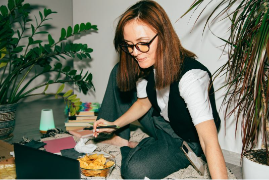 A [person sat on the floor working on a laptop.